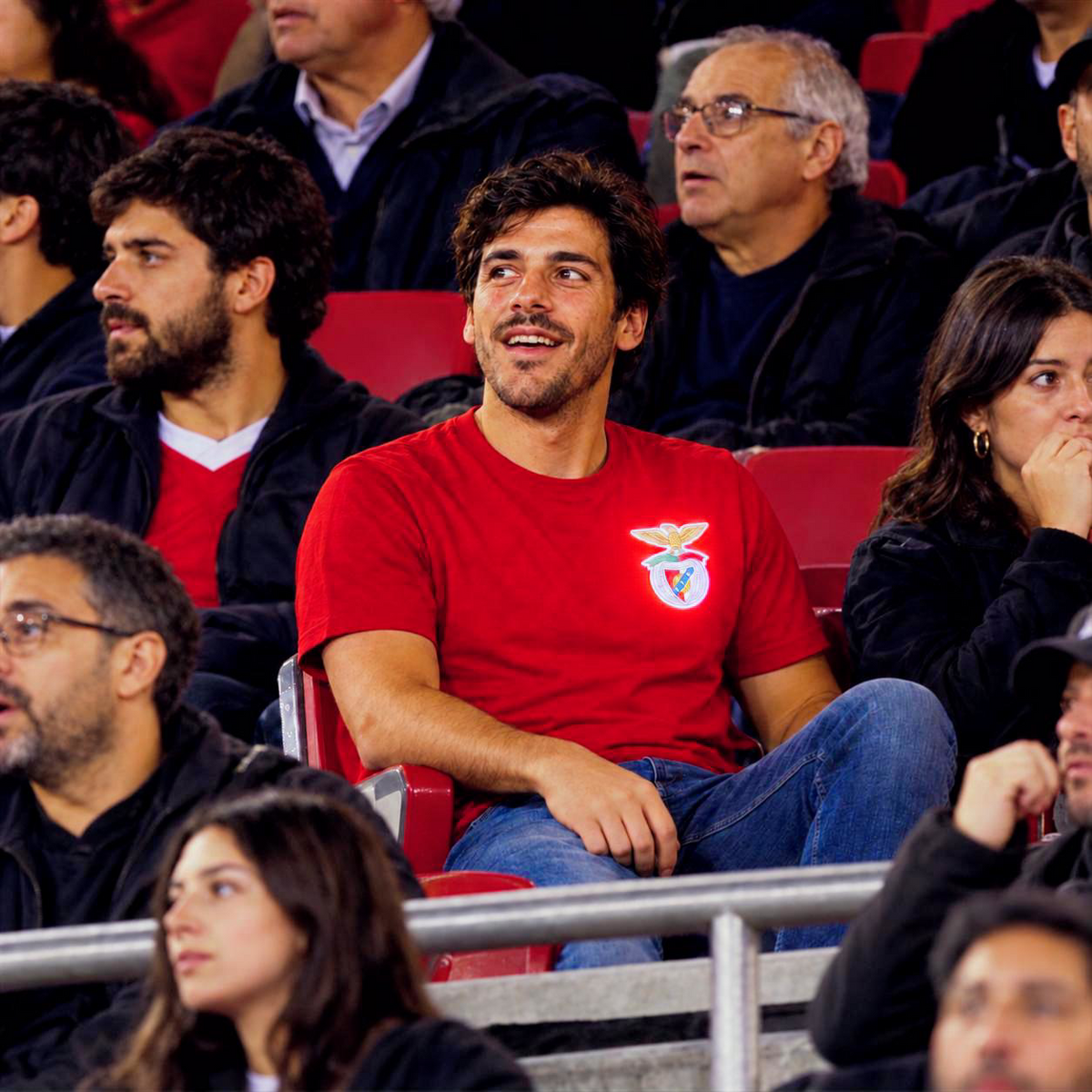 Pessoa a usar o emblema oficial iluminado pin LED do SL Benfica numa mochila, casaco ou camisola