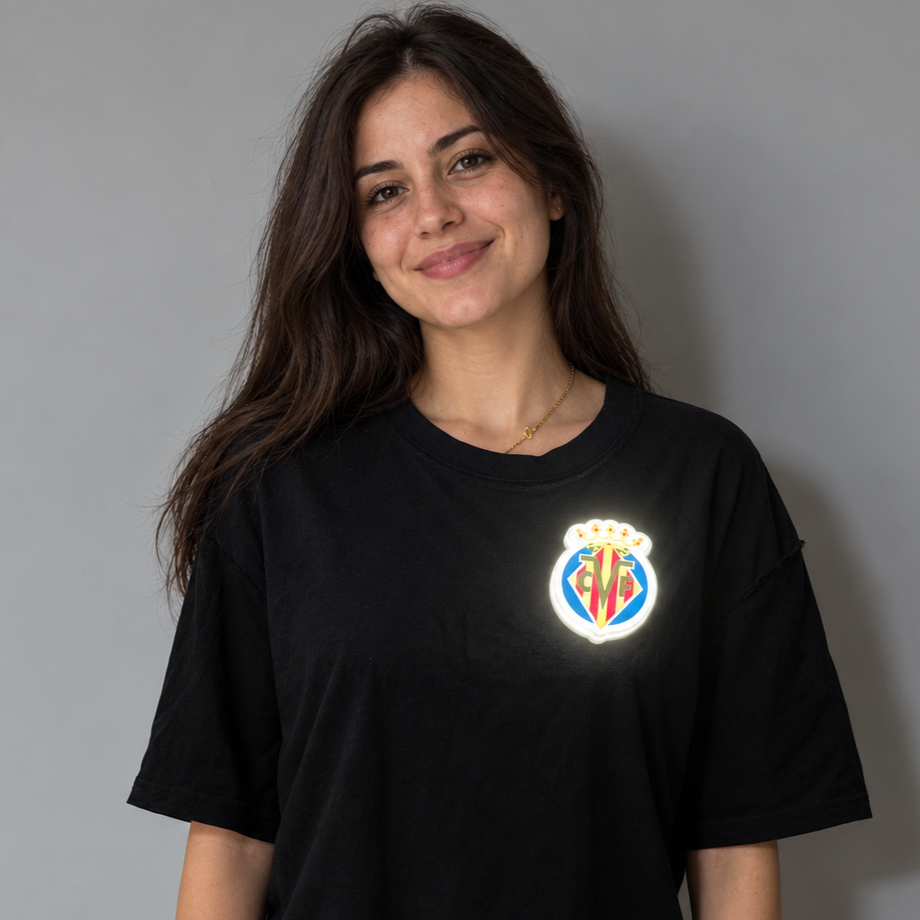 Persona llevando el escudo oficial iluminado Pin LED del Villarreal CF en una mochila, chaqueta o camiseta
