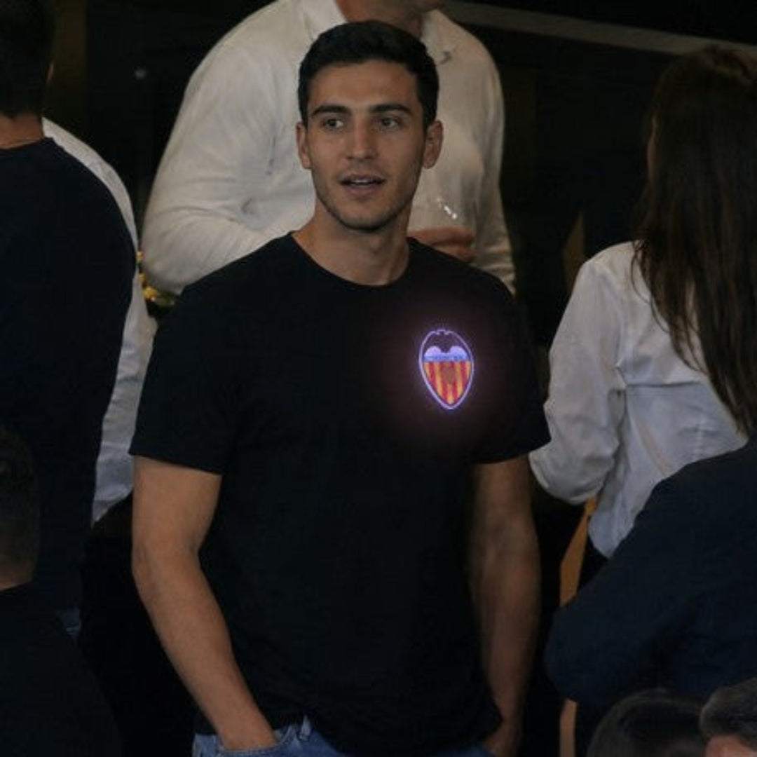 Persona llevando el escudo oficial iluminado del Valencia CF en una camiseta
